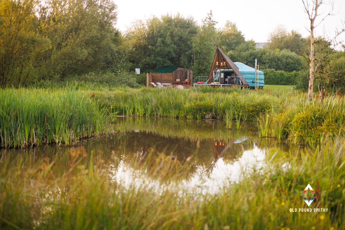 Yurt with a large A-frame porch in front of a lake in the north devon counrtyside