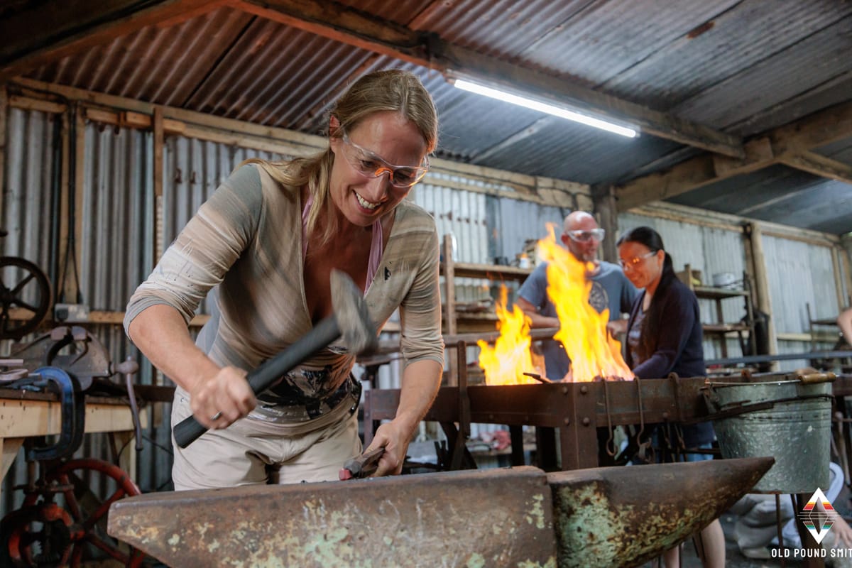Lady hammering at anvil during blacksmithing course